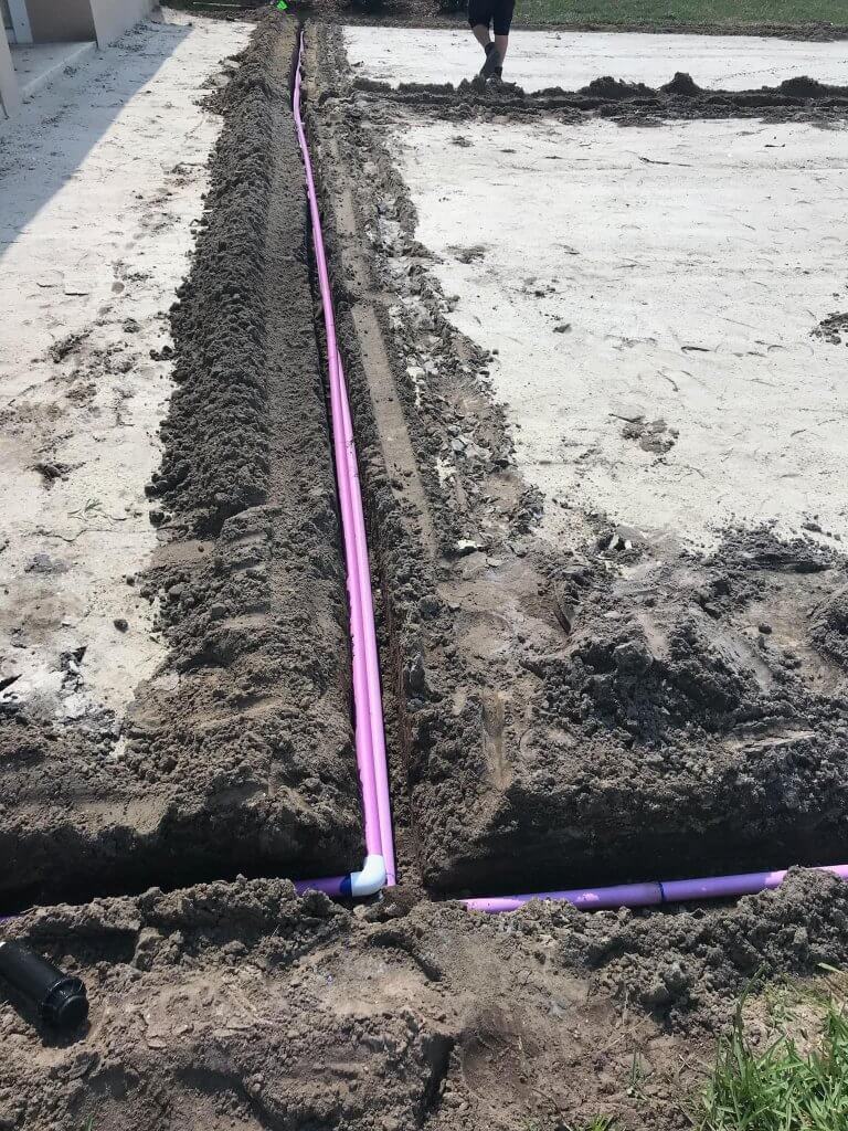 Installation of purple reclaimed water irrigation lines in freshly dug trenches for a new landscaping project by Pro Lawn Turf & Landscape